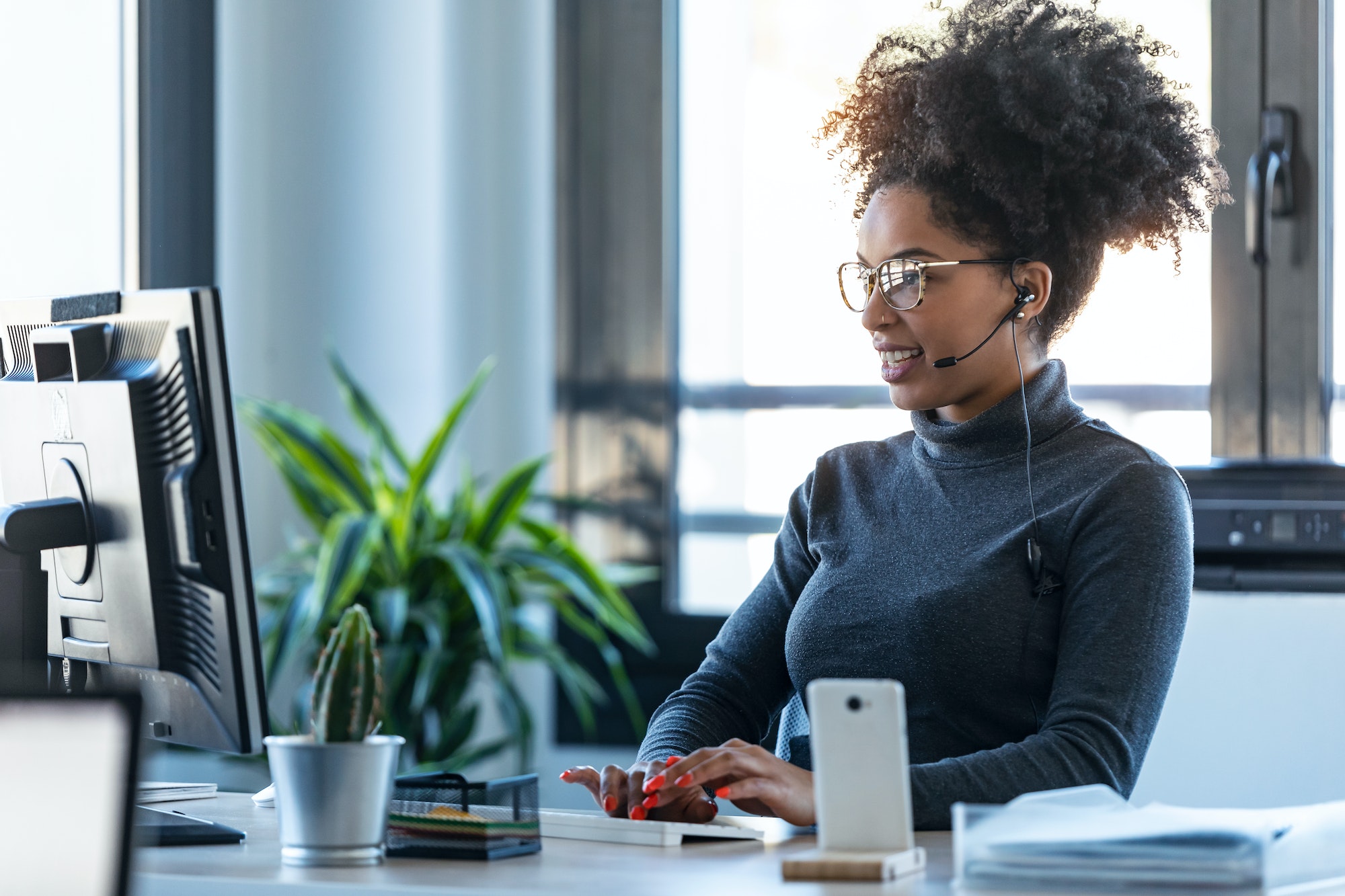 Afro business woman working while making video call with computer sitting in the office.