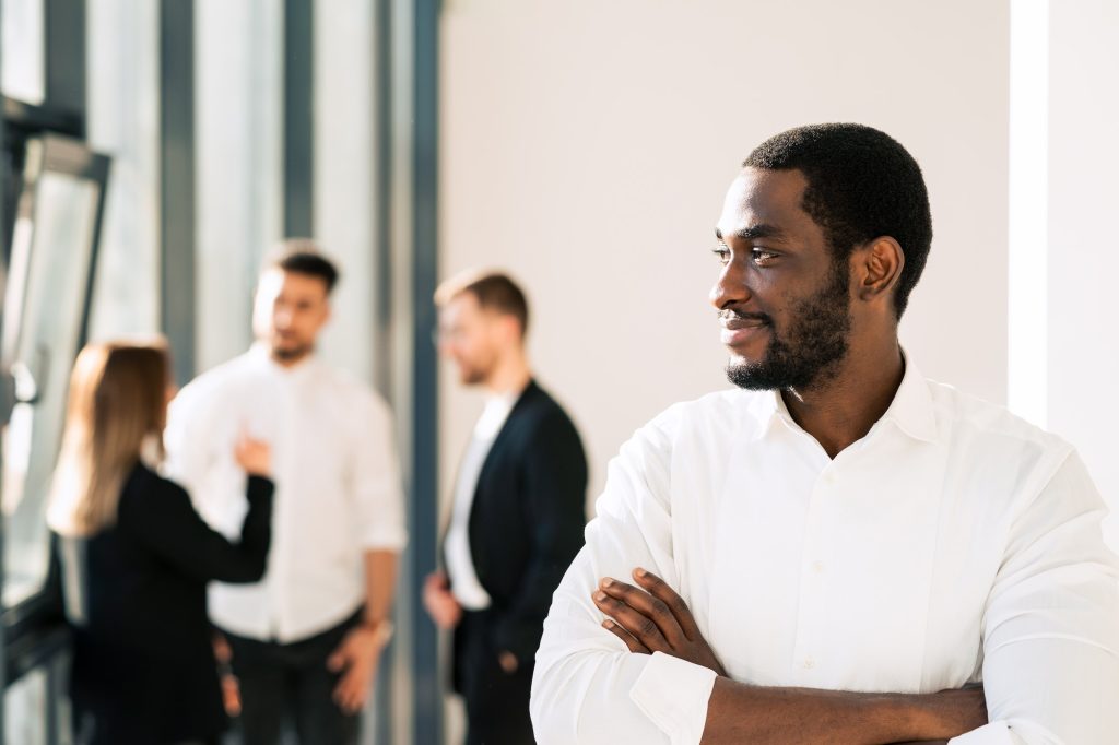 Black male executive and his employees in the background. Office worker portrait