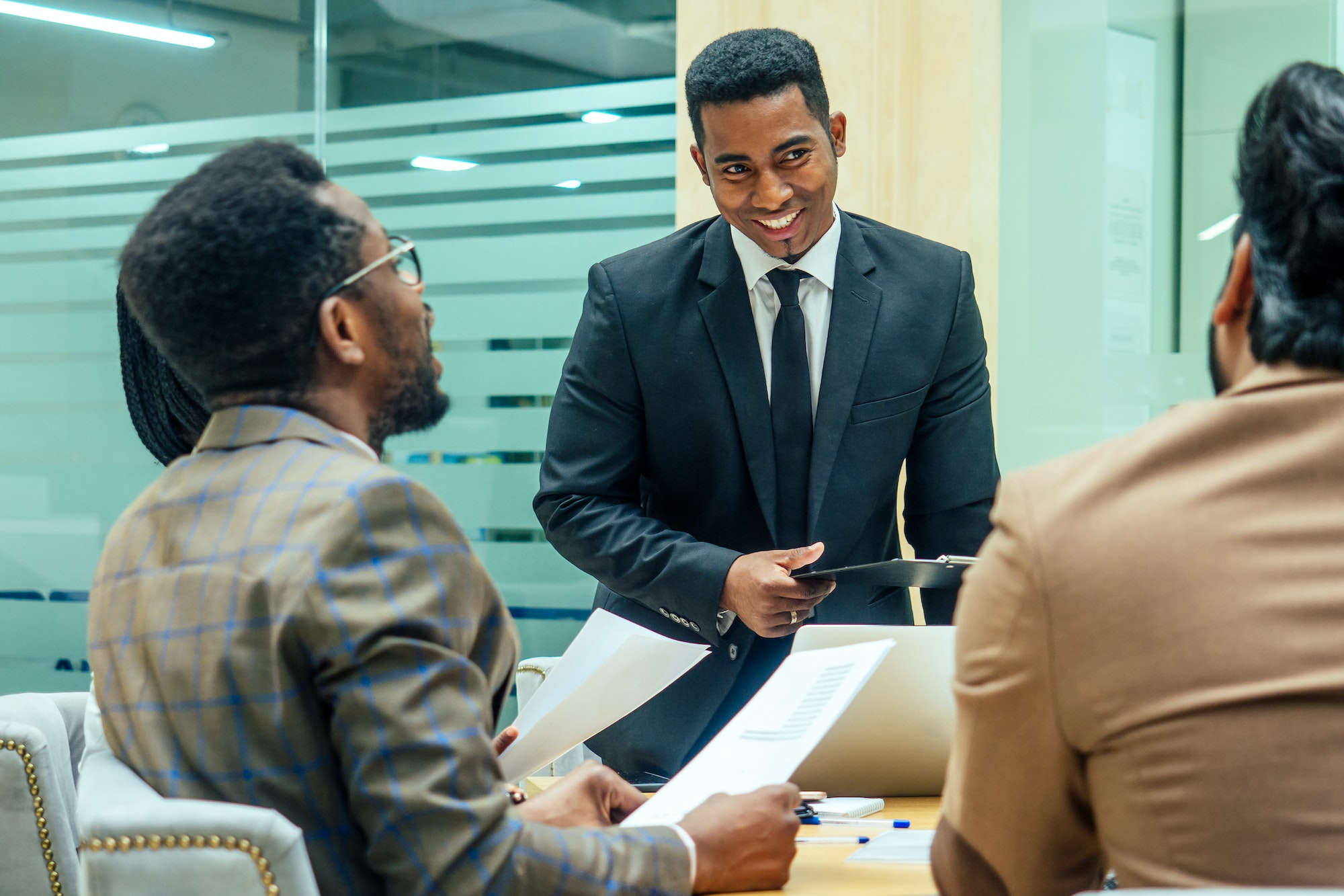 well-dressed business afro american men making a report to subordinate employees in a modern office